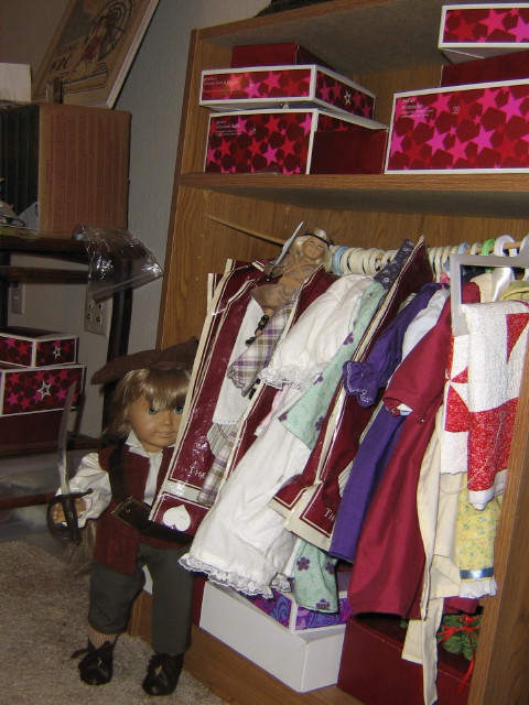 Kirsten, dressed as pirate Elizabeth Swann, and Mini Kit, in her Warrior Princess costume, hide behind the doll clothes rack, swords drawn.