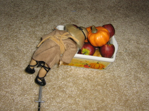 Mini Kit rummages through the apple and pumpkin bin, her foot on her sword.
