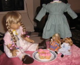 Kirsten in her summer dress, Mini Kit in a flour sack dress, Mini Nellie, and Pegleg Sally eat cupcakes.