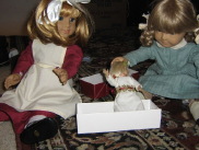 Kirsten shoves Mini Kit into her doll box with Nellie looking on.